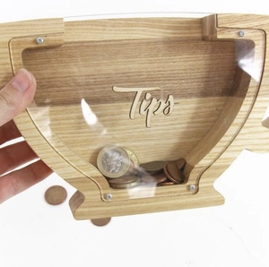 Detail of wooden coffee cup shaped tip jar with transparent acrylic panel and wood grain