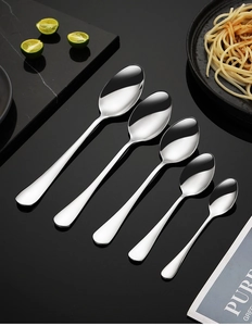 Detail of five mirror-polished stainless steel spoons in various sizes on black background