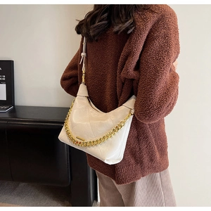 White quilted PU leather bucket bag with gold chain strap detail shown on shoulder