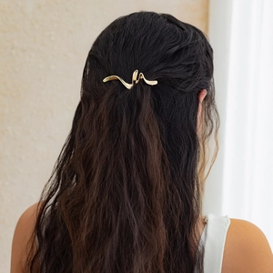 Detail of a wavy gold minimalist metal hair claw clip worn on long wavy brown hair
