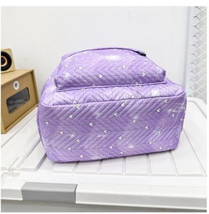 Detalle de mochila acolchada morada con patrones bordados de corazones y estrellas