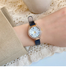 Elegant women's quartz watch with black leather strap and pearl dial shown on a wrist
