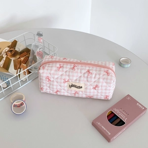 Quilted pink checkered pencil case with red bow patterns and hisocute label on a desk
