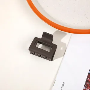 Close-up of matte coffee brown hair claw clip with rectangle hollow design on desk