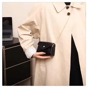 Detail showing high-quality black faux crocodile skin texture and gold chain on small bag