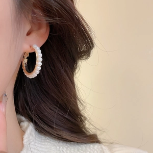 Elegant C-shaped pearl earrings with gold base shown on model for a minimalist aesthetic