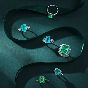 Detail of luxury S925 silver rings with emerald and aquamarine stones on a silk ribbon