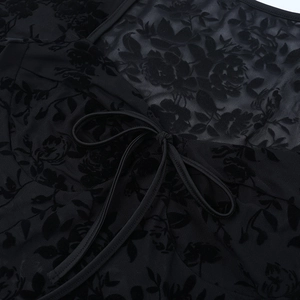 Détail du haut en dentelle noire transparente avec flocage floral et cordon de serrage