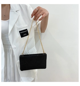 Detailed close-up of a black rhinestone clutch bag with a metallic gold chain strap