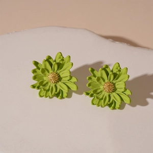 Detailed shot of green daisy earrings with golden stamen on a white stone base