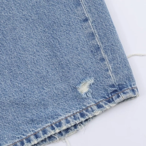 Gros plan détaillé du tissu denim bleu avec des trous déchirés et des bords effilochés