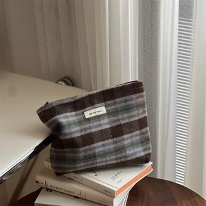 Detailed view of the thick tweed fabric texture and vintage plaid pattern on makeup bag