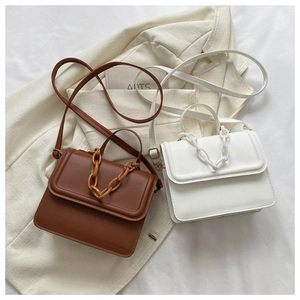 Brown and white PU leather crossbody bags with chunky chain detail on a suit blazer