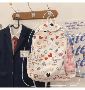 Close-up of white heart print backpack with a cute pink flower plush pendant and side pocket
