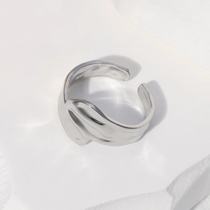 Close-up of silver irregular wave texture stainless steel open ring on a stone texture base