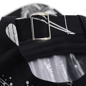 Close-up of adjustable silver metal buckle on black baseball cap with printed pattern