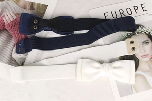Detail of navy and cream elastic waist belts with large fabric bow and metal snap buttons