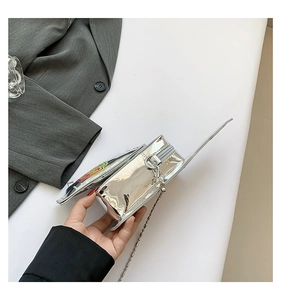 Detail of silver reflective mini round bag with metal chain and zipper closure