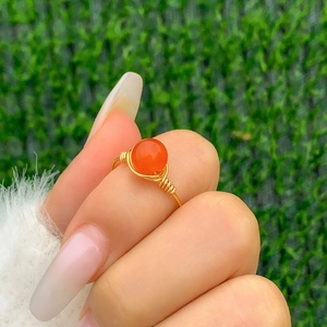 Detail of handmade wire wrapped gold ring with a vibrant orange carnelian gemstone bead