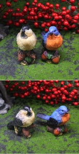 Dettaglio di uccelli in resina con piume su base di pigna per decorazioni da giardino