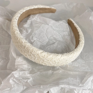 Close-up of elegant beige floral lace headband with non-slip lining on white paper