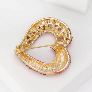 Detail view of the gold heart brooch back showing the pin fastener and red gemstone inlay