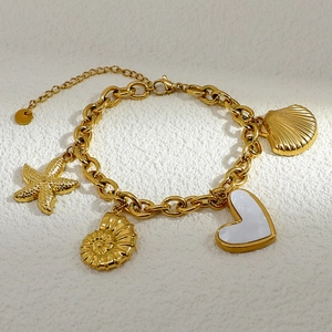 Macro shot of 18K gold plated ocean charm bracelet with starfish and shell pendants