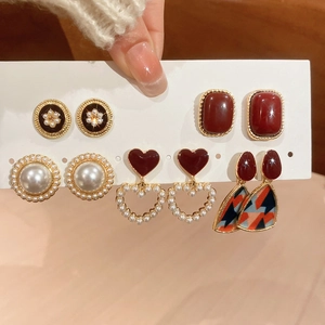 Close-up of five pairs of vintage resin pearl earrings with heart and floral designs