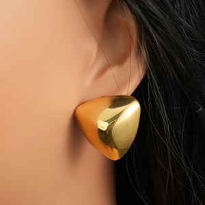 Macro detail of chunky gold triangle stud earrings worn on model for jewelry display