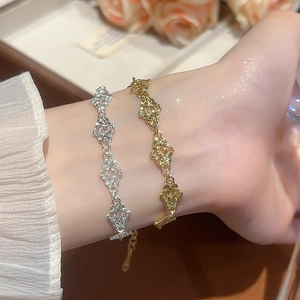 Detailed view of hollow lace-style clover leaf bracelets in gold and silver finishes