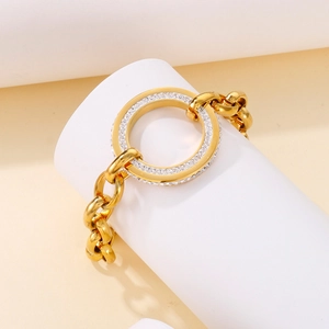 Detail view of a gold chain bracelet with a sparkling crystal-encrusted round link clasp