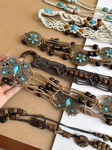 Close-up of bohemian woven belts with acrylic beads, metal butterflies and wooden buckles