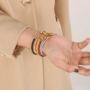 Detailed view of 5-piece woven C-shape open bracelets with gold bead tips on a model