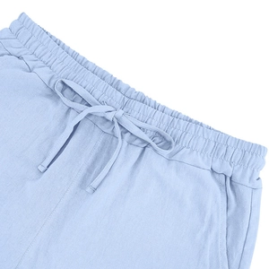 Detail of light blue linen shorts featuring elastic waistband and adjustable drawstring