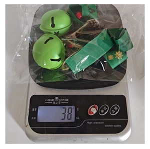 Detailed view of Christmas bells with ribbon and pine cones weighing 38g on scale