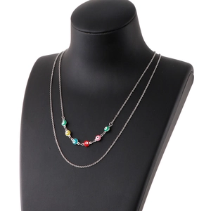Double-layered gold necklace featuring six colorful evil eye beads on black neck mannequin