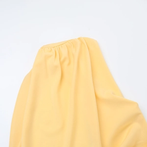 Detail of the yellow dress showing the intricate pleated shoulder and stitching craftsmanship