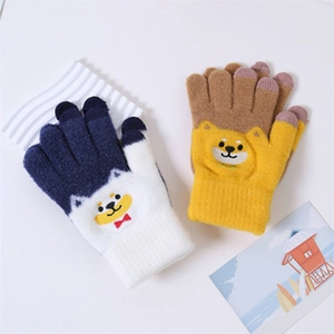 Close-up of knit winter gloves with cute cartoon Shiba Inu patterns in blue and brown colors