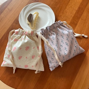 Detail of floral cotton drawstring pouches on wood background for small item storage