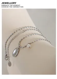 Detail of silver titanium necklace with freshwater pearl and oval pendant on a soft display