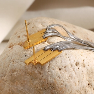 Detail of 18K gold plated geometric drop earrings with long silver tassel chains