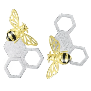 Macro shot of silver honeycomb earrings with gold bee and brushed metal finish details