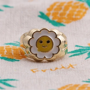 Macro shot of gold plated flower ring with yellow smiley face enamel details