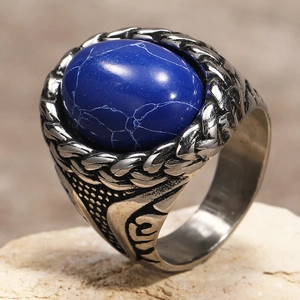 Close-up of vintage steel ring with oval blue textured stone and braided edge detail