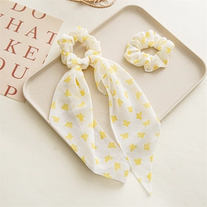 Detail of white chiffon scrunchie and ribbon with yellow butterfly patterns in a tray