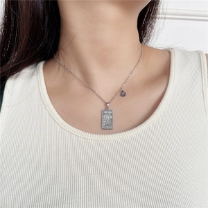 Scorpio tarot necklace detail showing rectangular silver pendant on ribbed white vest