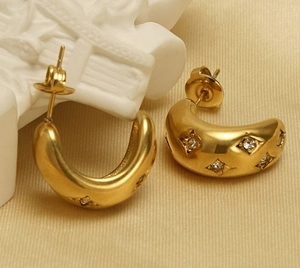 Macro detail of gold chunky hoop earrings with star-set cubic zirconia on silk cloth
