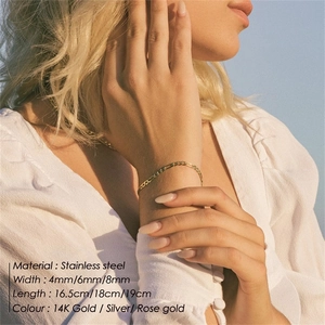 Close-up of gold stainless steel Figaro chain bracelet worn outdoors in sunlight
