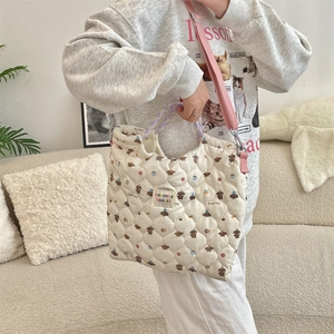 Quilted off-white tote bag featuring dog illustrations and purple handles in a home setting