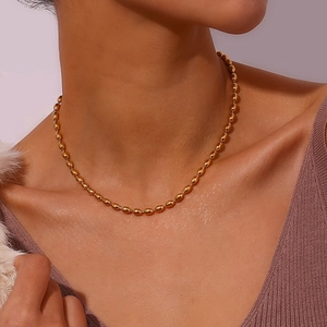 Detailed view of the 18K gold plated oval bead chain necklace worn by a fashion model